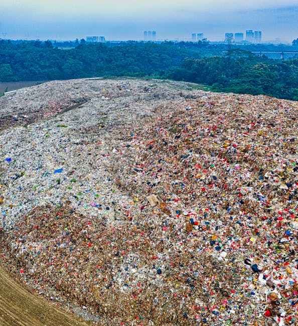 An aerial view of a rubbish removal scene showing three individuals sorting through a large pile of waste and debris outdoors. The scene includes various types of trash such as plastic bags, cardboard